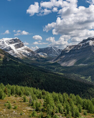 Fototapeta na wymiar Wilderness views in Banff National Park during summer time with snow capped mountains on a blue sky, clouds day. Beautiful nature in Alberta, British Columbia