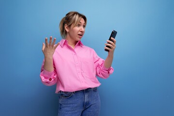 pretty businesswoman in pink shirt chatting in smartphone on studio background with copy space