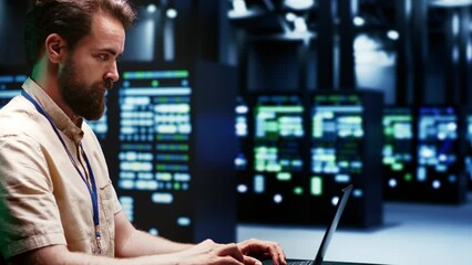 Skilled IT programmer imputing high tech facility hub disaster recovery plan on laptop to provide smooth restoration of service, limiting damage and maximizing operations uptime