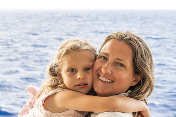Mother and daughter in loving moment at sea. 