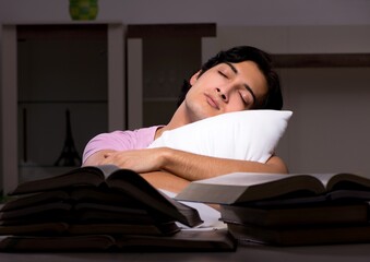 Obraz premium Male handsome student preparing for exams late at home