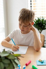 Cute boy doing school homework at home. Distance education. Online education.