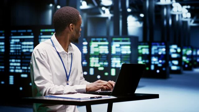 African american serviceman evaluating mainframes helping enterprises manage databases and store files. Professional inspecting server farm electronics used for high performance computing