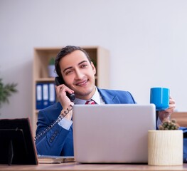 Young male employee drinking coffee during break
