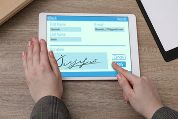 Electronic signature. Woman using tablet at wooden table, closeup