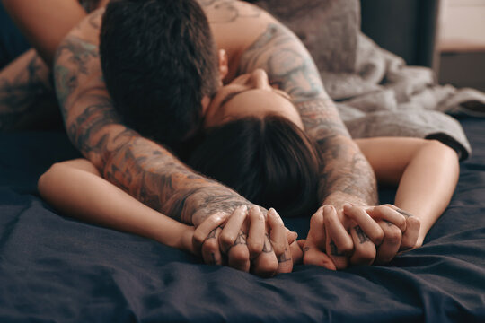 Passionate couple having sex on bed, focus on hands
