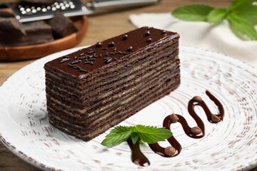 Tasty Spartak cake and mint on white plate, closeup