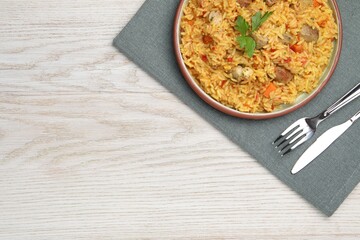 Delicious pilaf with meat served on white wooden table, top view. Space for text