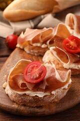 Board of tasty sandwiches with cured ham, tomato and cream cheese on table, closeup