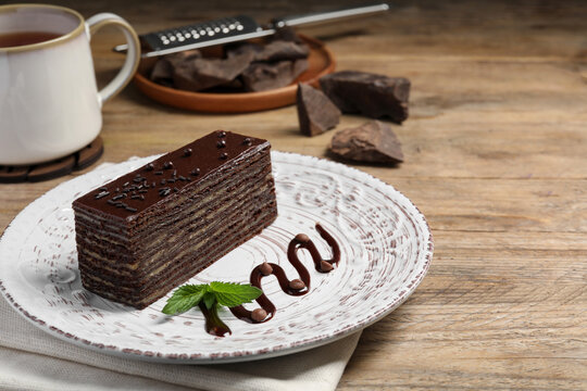 Tasty Spartak cake and mint on wooden table, space for text