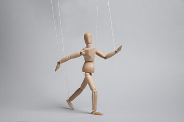 One wooden puppet with strings on light grey background