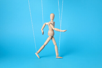 One wooden puppet with strings on light blue background