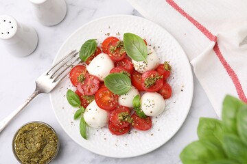 Tasty salad Caprese with tomatoes, mozzarella balls and basil served on white marble table, flat lay