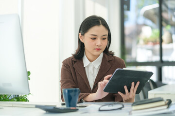 Charming young startup businesswoman using digital tablet, planning a project in office