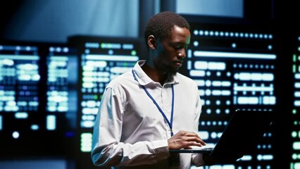African american meticulous employee walking through server rows providing vast computing resources and storage, enabling artificial intelligence to process massive datasets for training and inference - Powered by Adobe
