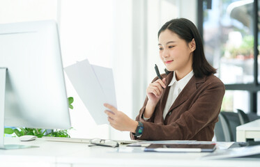 Charming caucasian female manager reading information on document, working in modern workplace.