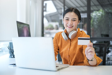 Beautiful asian woman holding credit card and using computer laptop. Concept of online shopping, e-commerce, internet banking.