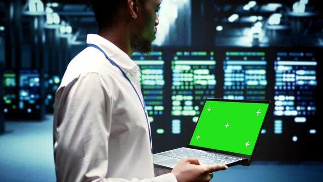 Developer using chroma key laptop to do checkup on high bandwidth dedicated game servers, used to accommodate incoming traffic of online users joining from worldwide locations.