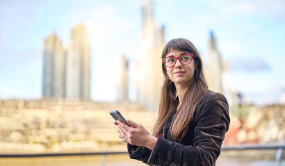 portrait beautiful caucasian young business woman in the street holding a cellphone