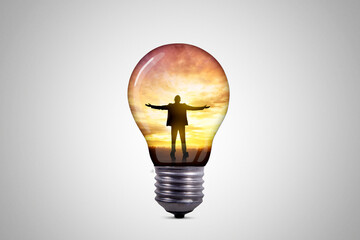 Silhouette of businessman celebrating raising arms inside a light bulb