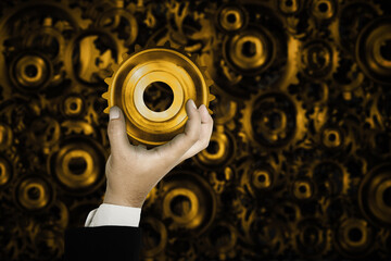 Businessman holding a metal cog wheel with blurred cog wheels