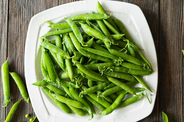 Fresh green peas on a wooden background. Summer crop of peas.