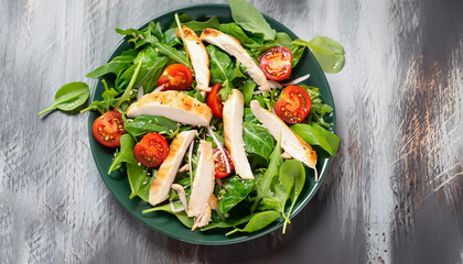 Fresh salad with chicken, tomato and greens (spinach, arugula) top view. Healthy food.
