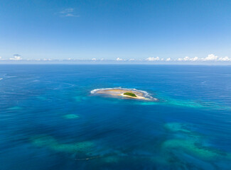 Beautiful Jobo Island surrounded by white sand. Blue sea under blue sky. Mindanao, Philippines.