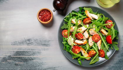 Fresh salad with chicken, tomato and greens (spinach, arugula) top view. Healthy food.