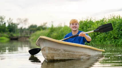 Foto op Canvas Joyful man tourists rowing boat with oars in river. Travel, vacation holiday and outdoor activity. © wattana