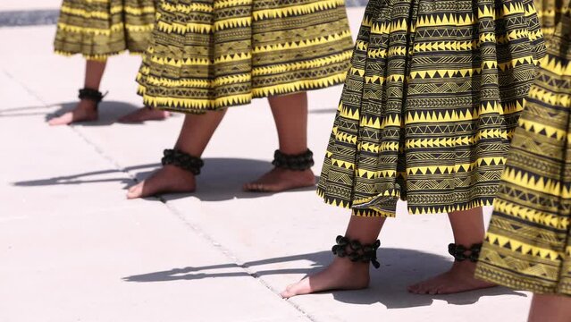 Hula dancers wearing kukui nut anklets take one step forward