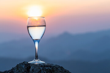 Glass of white wine and view to beautiful mountains sunset background.