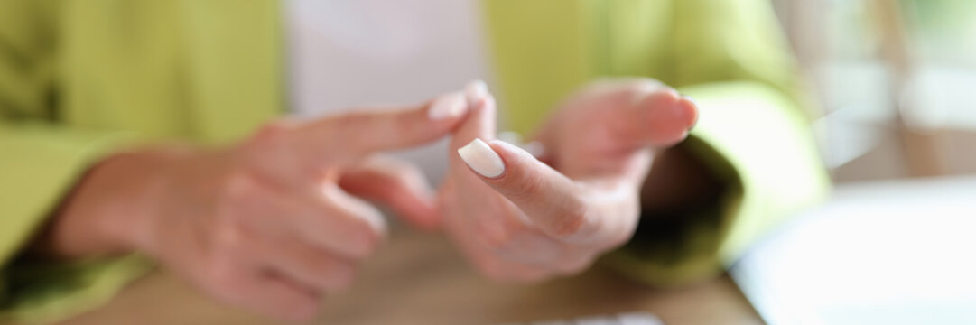 Woman counts on her fingers while sitting at table with computer keyboard.