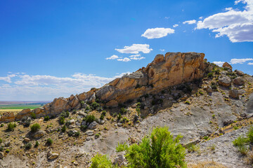 rocky mountain landscape with flat butte and blue sky with clouds