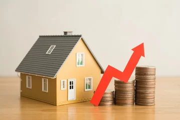  Red graph chart rising up on stack coins and house model on wooden table white wall background. Concept of money management for mortgage loan, fed increase interest rate, real estate price increase. © pla2na