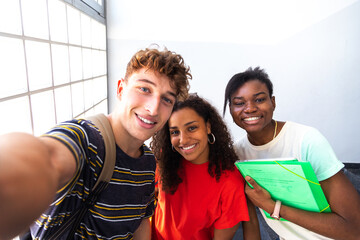 Happy group of multiracial teen friends taking a selfie in high school corridor. Back to school concept. Friendship