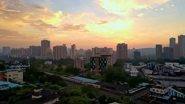 Aerial 4k city view of suburban Mumbai during a beautiful sunset revealing dense city. Mumbai drone at sunset with local railway train. Cinematic drone shot of Indian city with building rooftop 