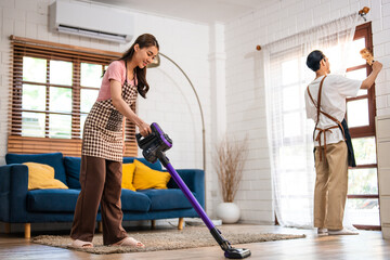 Fototapeta premium Asian attractive young man and woman cleaning house indoors together.