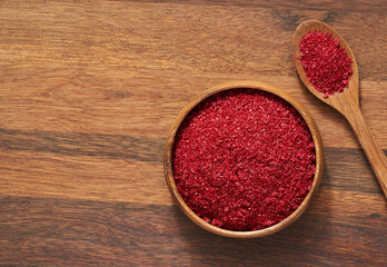 top view flat lay overhead red sumac sumak sumach powder in wood plate on wood table background. pile of sumac sumak sumach powder. heap of sumac sumak sumach powder food background
