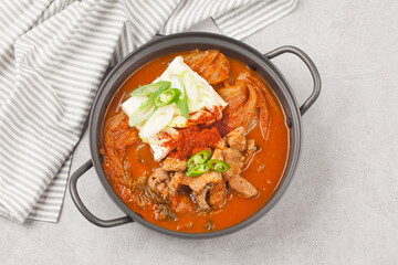 A stew made with kimchi, tofu, and pork