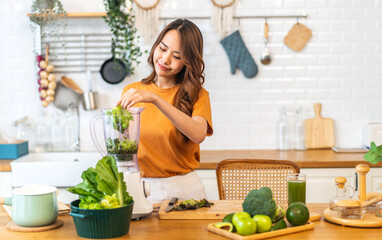 Portrait of beauty healthy asian woman making green vegetables detox cleanse and green fruit smoothie with blender.young girl drinking glass of smoothie, fiber, chlorophyll in kitchen.Diet, healthy