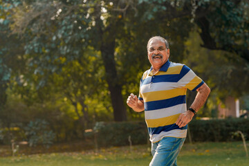 Indian old man running or jogging at park
