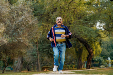 Indian old man running or jogging at park