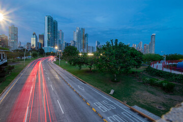 Fototapeta na wymiar Night or evening cityscape of Panama city with skyscrapers and beachfront. Light trails visible due to traffic flowing on the motorway below. Romantic modern photo of Panama city