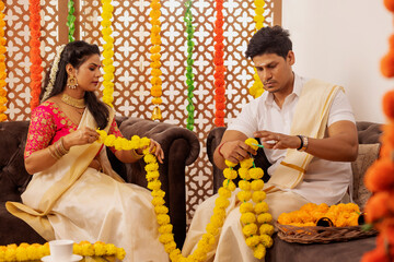 South Indian couple garlanding flowers together at home to celebrate Onam