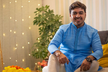 Portrait of cheerful young man in traditional outfit sitting at home on Raksha Bandhan