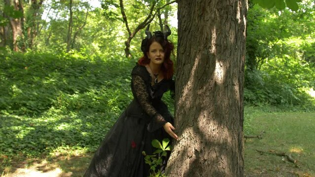 Succubus cosplay girl in the forest standing and dancing next to a tree, Full shot Slow Motion.