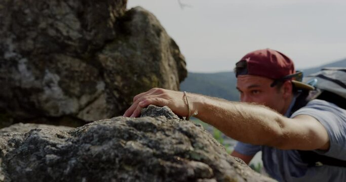athletic man climbing mountain, close-up hand reaching rocky grip, bouldering, hazy landscape in background, fit male free climb, placing hands to climbs high, altitude, cinematic shot, slow motion