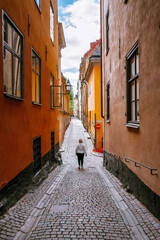 Fototapeta na wymiar Woman walking down a colorful cobble lane in the old town of Stockholm in Sweden