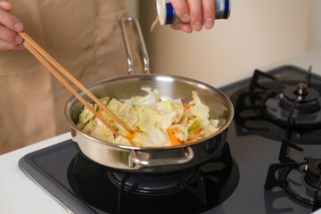 フライパンで野菜炒めを作る若い男性